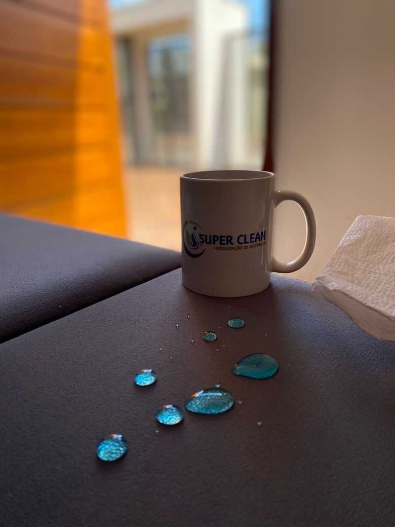 Gotas de água azul sobre sofá impermeabilizado pela Super Clean — líquido escorregando sem penetrar